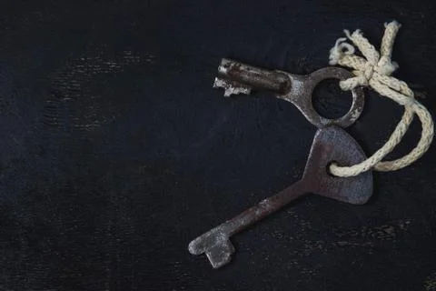 Two old keys tied with a white rope. The keys are on a black background.  Stock Photos