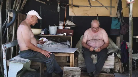 Two old man with bare torso playing cards in the village Stockbeeldmateriaal 134421253