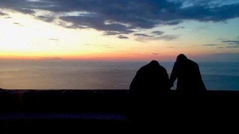 Two old men look at the sunset on the sea in Calabria, Italy. Stock Photos