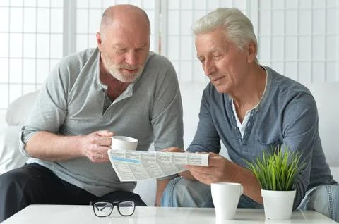 Two old men sitting at table and discussing news Stock Photos