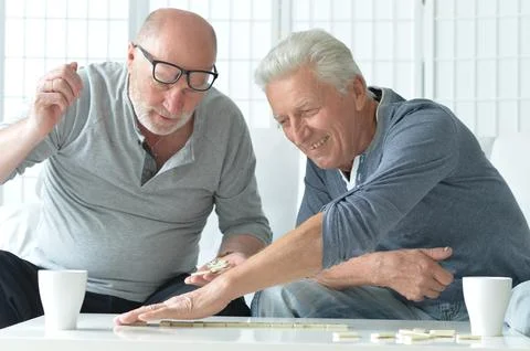 Two old men sitting at table and playing domino Foto stock