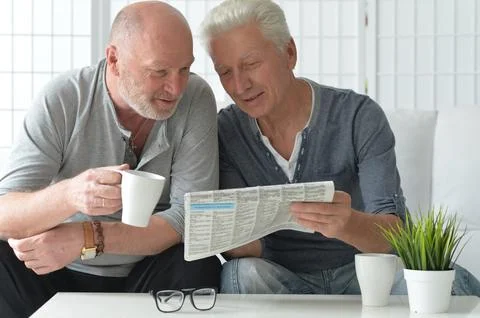 Two old men sitting at table and discussing news Stock Photos