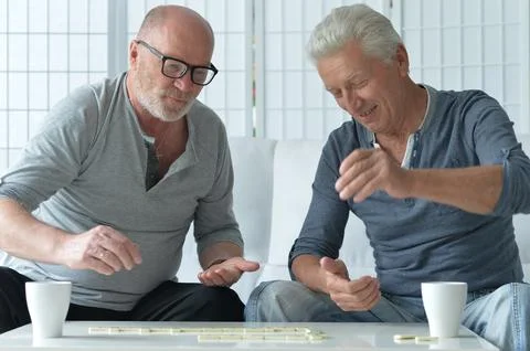 Two old men sitting at table and playing domino Stock Photos