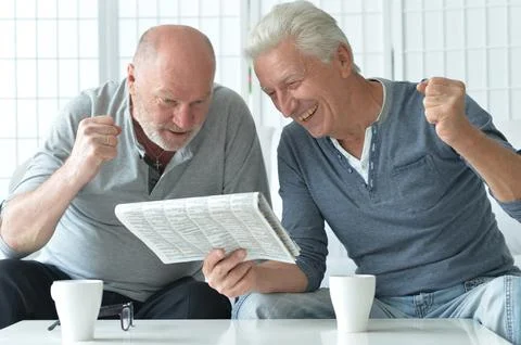 Two old men sitting at table and discussing news Stock Photos