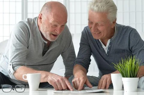 Two old men sitting at table and discussing news Stock Photos