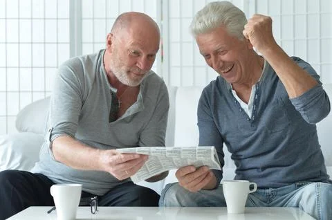 Two old men sitting at table and discussing news Stock Photos