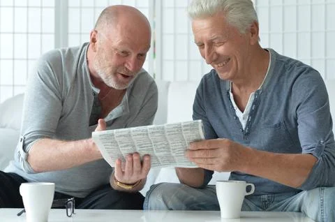 Two old men sitting at table and discussing news Stock Photos