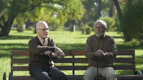 Two old men standing up from bench and walking different ways, quarrelling Stock Footage 99712957