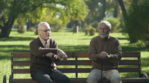 Two old men standing up from bench and walking different ways, quarrelling Stock Footage 99716451