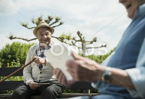 Two Old Men Using Tablet Computers In The Park