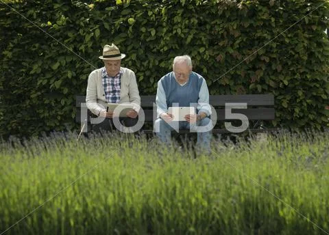 Two Old Men Using Tablet Computers In The Park