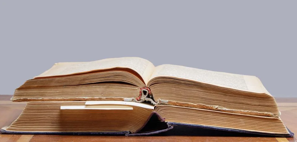 Two old open books with bookmarks lie on a wooden table Stock Photos