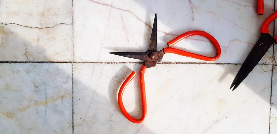 Two old red rusty scissors putting on white marble floor background Stock Photos