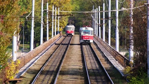 Two old red trams ride in a city park at sunny autumn day Stock Footage 143098467
