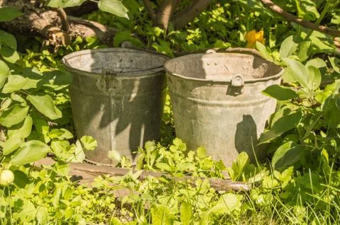Two old rusty iron buckets in the garden grass Foto stock
