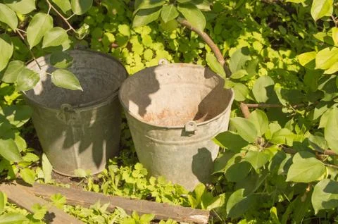 Two old rusty iron buckets in the garden grass Stock Photos