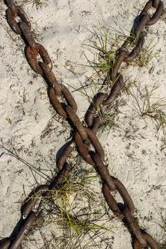 Two old rusty iron chains form X pattern to sand Foto stock
