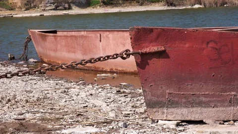 Two old rusty metal boats chained on a river bank on a sunny day Video stock 128287601