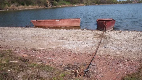 Two old rusty metal boats chained on a river bank on a sunny day Video stock 128287751
