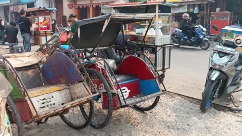 Two old rusty pedicab becak parked with motorbike Cikarang Indonesia Видео 348192880