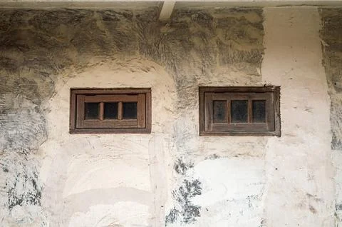 Two old, small rectangular wooden framed windows are set into a rough, text.. Stock Photos