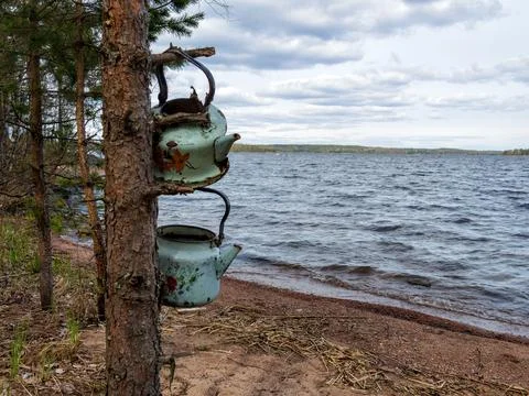 Two old teapots on the background of a calm lake. Two teapots are hanging on  Stock Photos