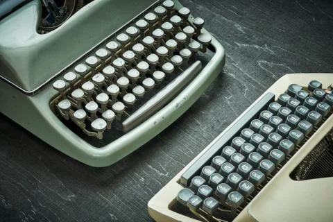Two old typewriters on a black table Stock Photos