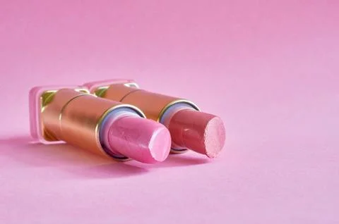 Two old used lipstick tubes lie on a pink background Stock Photos