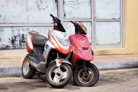 Two old worn mopeds stand alone at the edge of the road. Stock Photos