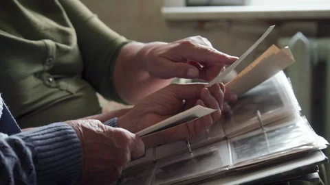 Two older adults softly flipping through cherished picture albums Stock Footage 321950136