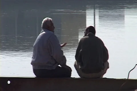 Two older men have a chat while sitting at the edge of the Euphrates River. Video stock 86753716
