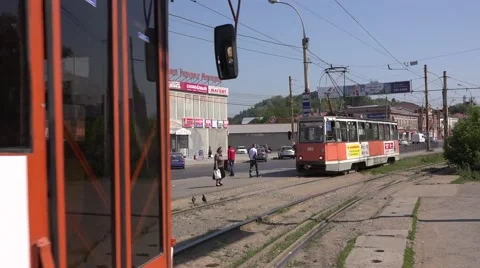 Two oncoming orange trams cross at a stop in Motovilikha borough Stock Footage 64638778