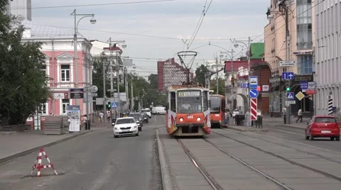 Two oncoming orange trams running at centrally located segregation Stock Footage 64638848
