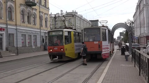 Two oncoming solo trams meet on segregated track near a stop Stock Footage 64638763
