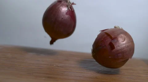 Two onions bounce in slow motion onto a cutting board - dutch shot Stock Footage 64627723