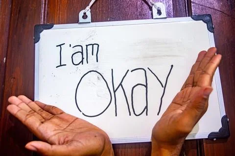 Two open hands under a whiteboard with I am OKAY message, symbolizing menta.. Stock-Fotos