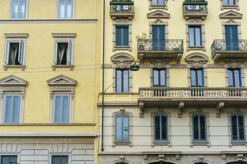 Two open windows on the wall of an old house with numerous closed windows and Stock Photos