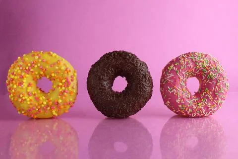 Two or three doughnut berliner pink yellow chocolate on a pink background sta Stock Photos