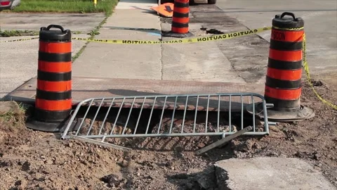 Two orange and black traffic delineator pylon barrel drums next to sidewalk Stock Footage 246137501