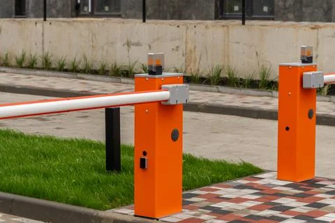 Two orange automatic parking gate barriers stand in place to control traffi.. Фото