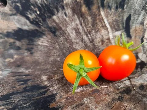 Two orange cherry tomatoes are placed on a wooden surface. Stock Photos