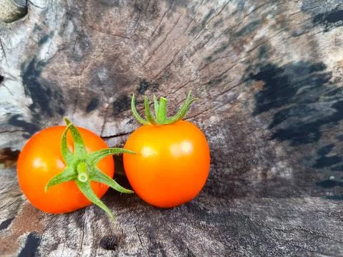 Two orange cherry tomatoes are placed on a wooden surface. Stock Photos