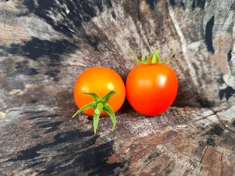Two orange cherry tomatoes are placed on a wooden surface. Fotos de archivo