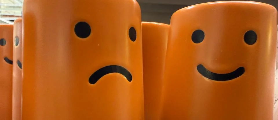 Two orange objects showing contrasting sad and happy emotions on a bright bac Stock Photos