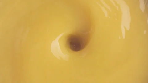 Two orange slices in circle shape drop into a orange juice swirl Stock Footage 147234939