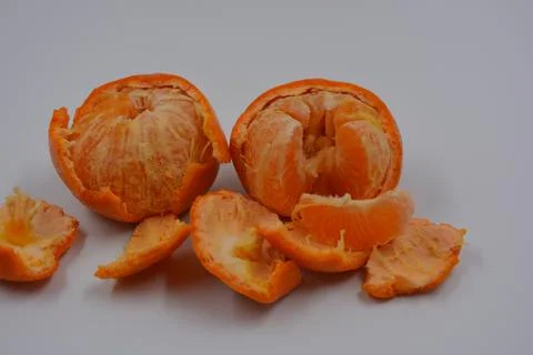 Two orange tangerines with peeled peels are on a white plastic. Stock Photos
