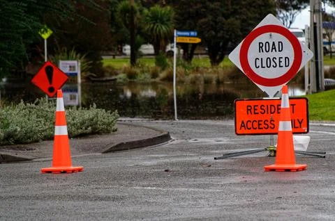 Two orange traffic cones help block off a flooded street. Stock Photos