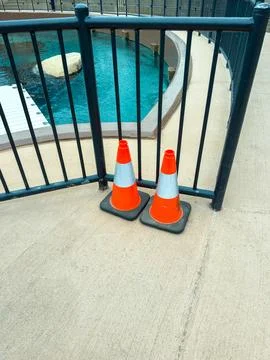 Two orange traffic cones placed near a pool in an outdoor area during the day Fotos Stock