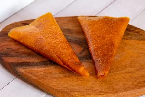 Two orange triangular fruit pastille pieces arranged on dark wooden board w.. Stock Photos