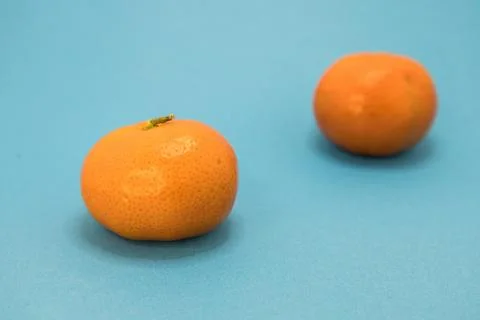 Two oranges on a blue background, one sharp in the foreground, the other soft Stock Photos